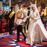 Anisha Rosnah tampil cantik dalam balutan ballgown bergaris leher tinggi. Gaun putih tersebut dilengkapi penutup kepala dan veil panjang menyapu lantai. Wanita berusia 29 tahun ini melengkapi penampilannya dengan tiara, sepasang anting, kalung, gelang dan cincin berhias berlian. Foto: AFP/IQBAL DATO HJ SELAMAT