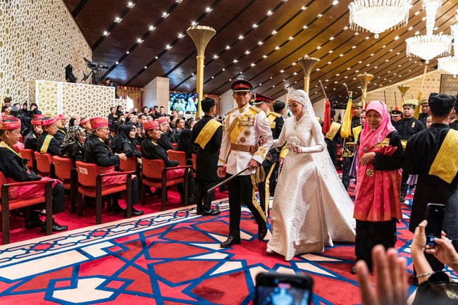 Pangeran Abdul Mateen terlihat gagah mengenakan busana resmi kerajaan. Beurpa jas dengan berbagai emblem, celana panjang sepatu pantofel serta topi. Foto: AFP/IQBAL DATO HJ SELAMAT