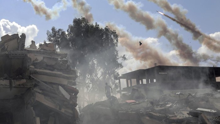 Rockets are fired from the Gaza Strip toward Israel over destroyed buildings following Israeli airstrikes on Gaza City, central Gaza Strip, Thursday, Oct. 19, 2023. (AP Photo/Mohammed Dahman)