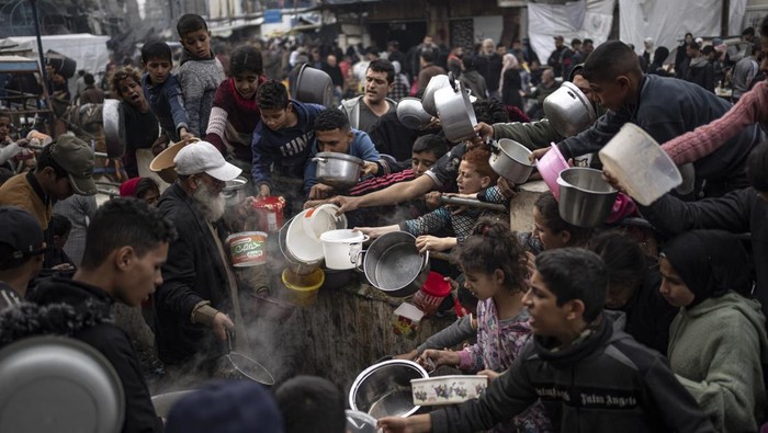 Palestinians line up for a free meal in Rafah, Gaza Strip, Thursday, Dec. 21, 2023. International aid agencies say Gaza is suffering from shortages of food, medicine, and other essential supplies as a result of the two-and-a-half-month war between Israel and Hamas. (AP Photo/Fatima Shbair)
