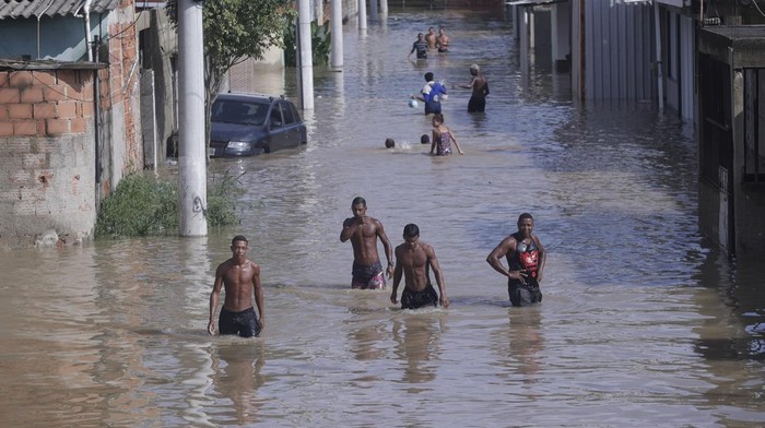 Brazil Floods Ingrid Monteiro carries her one-year-old daughter Aylla Perola over floodwaters outside their home after deadly, heavy rainfall in Duque de Caxias, Brazil, Sunday, Jan. 14, 2024. (AP Photo/Bruna Prado)