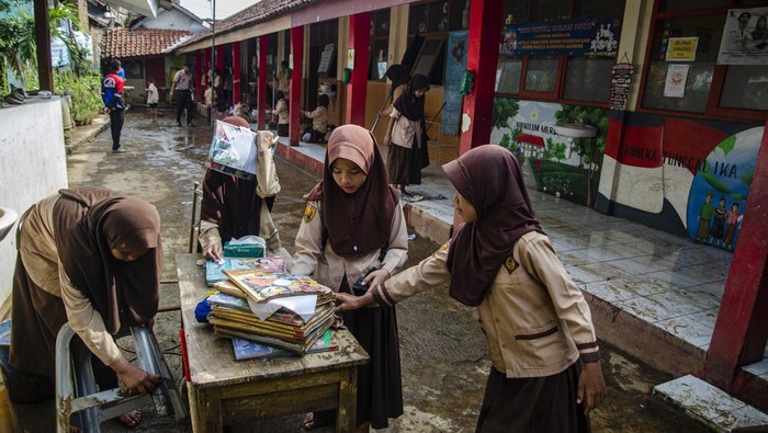 Guru membantu murid berjalan di atas kursi untuk menghindari lumpur dampak banjir di SDN Leuwi Bandung 01, Dayeuhkolot, Kabupaten Bandung, Jawa Barat, Senin (15/1/2024). Sejumlah sekolah di kawasan Kabupaten Bandung belum melaksanakan kegiatan belajar mengajar secara optimal akibat banyaknya fasilitas dan buku pedoman pelajaran yang rusak terdampak banjir beberapa waktu lalu. ANTARA FOTO/Novrian Arbi/nym.
