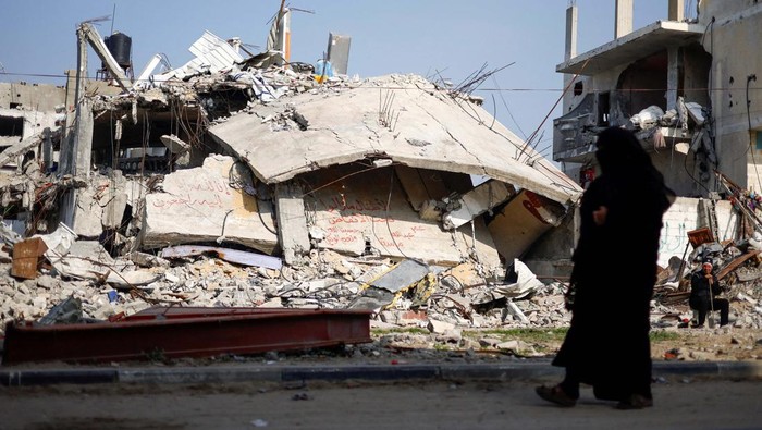 Ziad Mansour, a neighbour of the Abu Aweidah family, sits next to writing painted on a wall amid the rubble of the familys house, which was destroyed in a deadly Israeli strike amid the ongoing conflict between Israel and the Palestinian Islamist group Hamas, in Rafah, Gaza Strip, January 9, 2024. REUTERS/Mohammed Salem