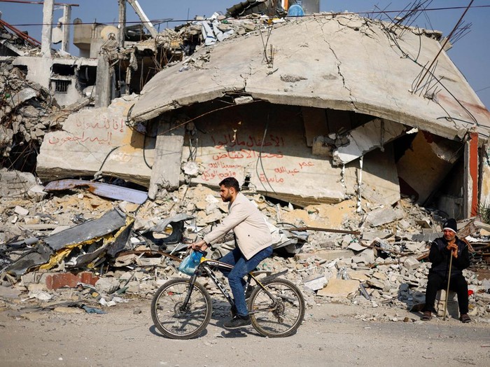 Ziad Mansour, a neighbour of the Abu Aweidah family, sits next to writing painted on a wall amid the rubble of the familys house, which was destroyed in a deadly Israeli strike amid the ongoing conflict between Israel and the Palestinian Islamist group Hamas, in Rafah, Gaza Strip, January 9, 2024. REUTERS/Mohammed Salem