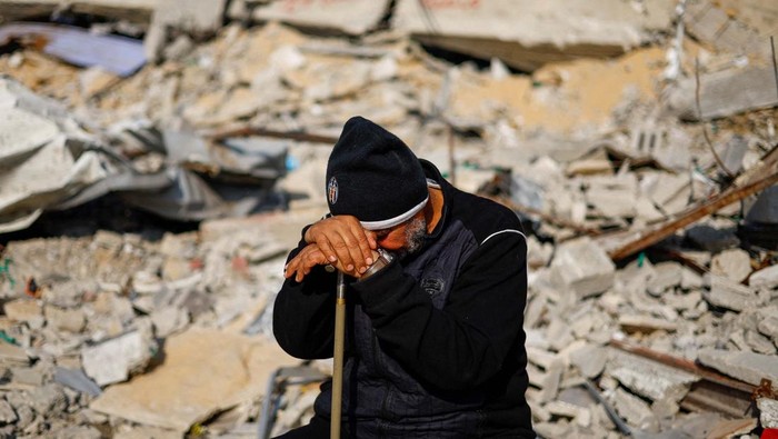 Israel Terus Serang Gaza, 60 Orang Tewas dalam Semalam Ziad Mansour, a neighbour of the Abu Aweidah family, sits next to writing painted on a wall amid the rubble of the family's house, which was destroyed in a deadly Israeli strike amid the ongoing conflict between Israel and the Palestinian Islamist group Hamas, in Rafah, Gaza Strip, January 9, 2024. REUTERS/Mohammed Salem