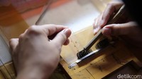 Pekerja mengukur bulu mata palsu dengan sedang dibuat. 