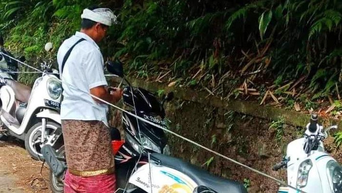 Motor milik pemedek yang parkir sembarangan di sepanjang jalan menuju Pura Besakih diikat tali plastik, Senin (15/1/2024). (Istimewa)