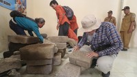 Arkeolog dari Balai Pelestarian Kebudayaan (BPK) wilayah XI Jawa Timur mengamati batu bata kuno yang diamankan di Balai Desa Kayunan, Kediri, Jawa Timur, Senin (15/1/2024).  