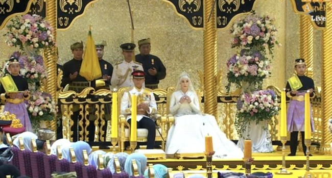 Potret saat Pangeran Mateen dan Anisha bersanding di pelaminan. Standing flower bernuansa ungu menambah keindahan dekorasi pelaminan. Foto: YouTube/rtbnews