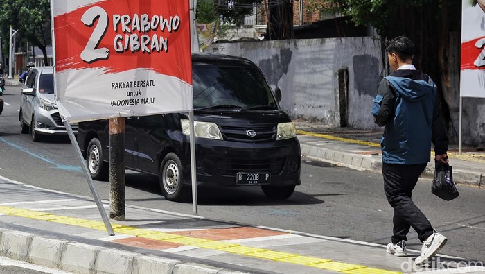 Pejalan kaki menghindari Alat Peraga Kampanye (APK) yang terpasang di jalur pedestrian di Jl Cemara, Jakarta Pusat, Selasa (16/1/2025). Pemasangan APK yang menyerobot trotoar itu dikeluhkan warga seperti terekam dalam akun instagram koalisi pejalan kaki. APK dinilai merampas hak pejalan kaki dan merusak fungsi trotoar.