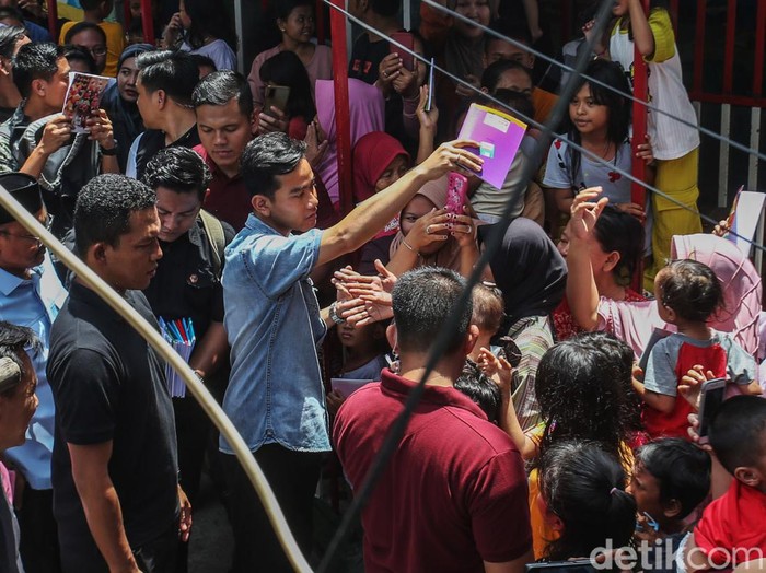 Calon Wakil Presiden nomor urut 02 Gibran Rakabuming Raka membagikan buku di Warakas, Jakarta Utara, Selasa (16/1/2024).