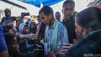 Gibran berjalan sambil membagi-bagikan buku tulis kepada anak-anak.