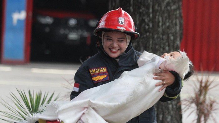 Seorang guru mempraktekkan cara menyelamatkan korban dalam kegiatan Edukasi Penanggulangan Bencana Kebakaran di Markas Pemadam Kebakaran Kota Malang, Jawa Timur, Selasa (16/1/2024). Kegiatan tersebut diadakan untuk memberikan edukasi mengenai langkah-langkah penanganan bencana kebakaran sekaligus pengenalan profesi Pemadam Kebakaran kepada sekitar 80 siswa Taman Kanak-kanak. ANTARA FOTO/Ari Bowo Sucipto/foc.