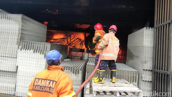 Pemadam kebakaran melakukan pemadaman kebakaran toko material di Cianjur, Selasa (16/1/2024).