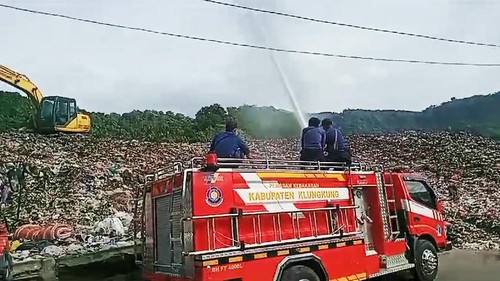Petugas Damkar Klungkung melakukan penyiraman Eco Enzym pada gunungan sampah di TPA Sente, Selasa (16/1/2024). (Putu Krista/detikBali).