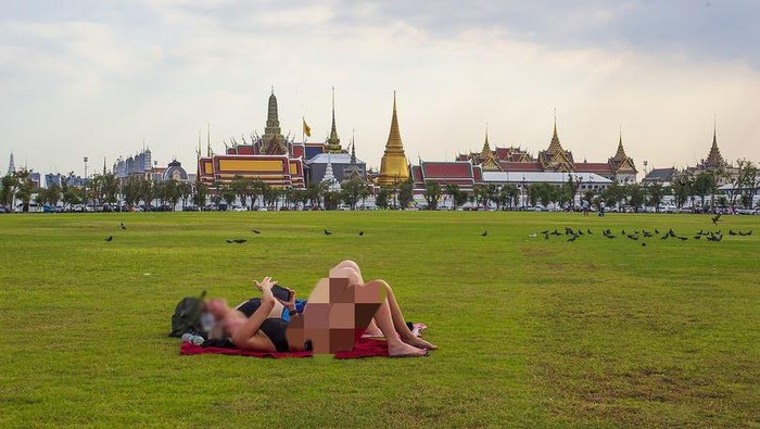 Turis berjemur dengan pakaian terbuka di kuil suci Thailand.