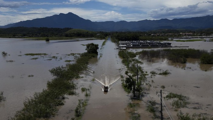Residents cross a submerged road by boat after deadly rainfall in Duque de Caxias, Brazil, Monday, Jan. 15, 2024. (AP Photo/Bruna Prado)