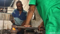 Sumardi bersama Muhammad Rofiq sedang menepa besi yang suda dipanaskan untuk dibuat plaser pesanan konsumen.
