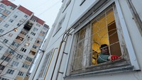 Seorang wanita membersihkan pecahan kaca di samping blok apartemen bertingkat yang rusak menyusul laporan serangan drone di Voronezh, Rusia 16 Januari 2024.
