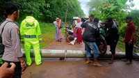 Warga dan polisi tampak bahu membahu membantu warga agar bisa melintas tiang listrik yang roboh.