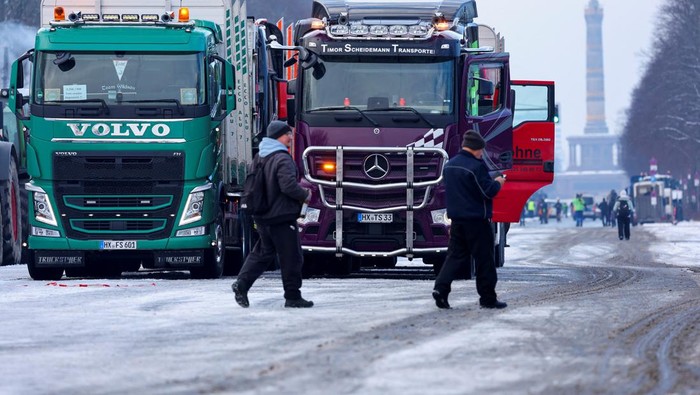 A person stands next a truck with a banner that reads 'stop tolls and CO2 rip-offs', as German truckers protest against a motorway toll increase of the so-called German Ampel coalition government, in Berlin, Germany January 18, 2024. REUTERS/Fabrizio Bensch