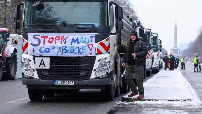 Pengemudi Truk di Jerman Protes Kenaikan Tarif Tol A person stands next a truck with a banner that reads 'stop tolls and CO2 rip-offs', as German truckers protest against a motorway toll increase of the so-called German Ampel coalition government, in Berlin, Germany January 18, 2024. REUTERS/Fabrizio Bensch
