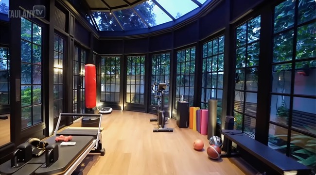 Ruangan kerja Ashraf tersambung dengan gym beratap kaca yang dibangun BCL semasa pandemi. Tadinya ini taman. Selain gym, di sini juga bisa jadi studio pilates. Pelatihnya yang ke rumah, kata penyanyi yang juga aktris ini. (Foto: YouTube/Taulany TV)