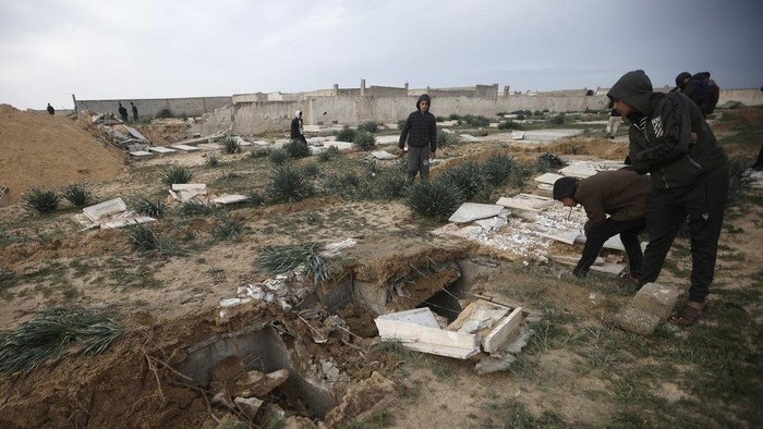 Palestinians inspect damaged graves following an Israeli tanks raid over a cemetery in Khan Younis refugee camp, southern Gaza Strip, Wednesday, Jan. 17, 2024. (AP Photo/Mohammed Dahman)