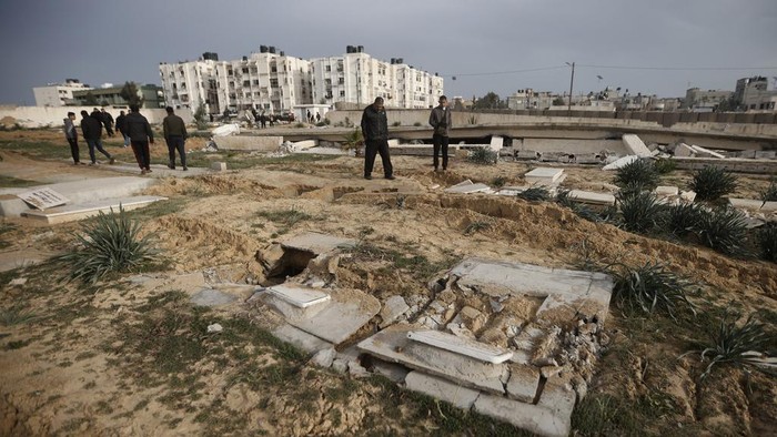 Palestinians inspect damaged graves following an Israeli tanks raid over a cemetery in Khan Younis refugee camp, southern Gaza Strip, Wednesday, Jan. 17, 2024. (AP Photo/Mohammed Dahman)