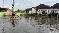 Seorang siswa sedang melintasi halaman sekolah SD Negeri Banjarsari yang tergenang banjir.