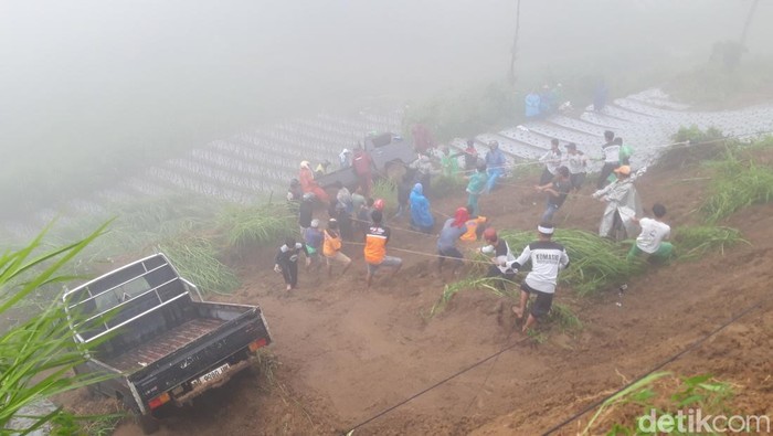 Warga bergotong-royong mengevakuasi mobil yang terjun ke ladang akibat keterjang tanah longsor di jalan Boyolali-Magelang di Selo.