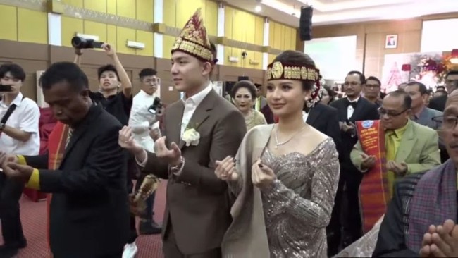 Resepsi tersebut digelar ketika Anggi tengah hamil muda. Meski demikian pelantun lagu Tak Segampang Itu tetap terlihat aktif dan bersemangat mengikuti rangkaian prosesi dengan menggunakan adat Batak. Foto: YouTube/Kenjiro dan Anggi