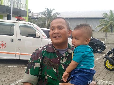 Babinsa Pemalang, Serma Kurdi, menggendong bayi 15 bulan, salah satu korban selamat dari kecelakaan bus yang terjun dari tol Pemalang KM 320, Minggu (21/1/2024).