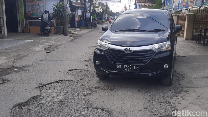 Mobil melintas di Jalan Pimpinan Medan yang kondisinya rusak. (Felicia Br Sihite/detikSumut)