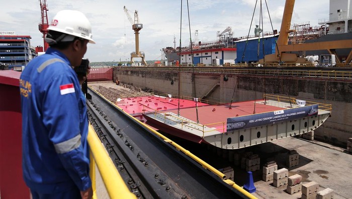 Pekerja mengawasi proses peletakan llunas kapal (keel laying) Landing Dock pesanan Negara Filipina di Dok Semarang PT PAL Indonesia di Surabaya, Jawa Timur, Senin (22/1/2024). Kapal yang masuk dalam kelas Llyod's Register (LR) sepanjang 124 meter, berat 7.200 ton, kecepatan maksimal 16 Knots serta berkapasitas 680 orang tersebut ditargetkan akan selesai pada 2026. ANTARA FOTO/Moch Asim/foc.