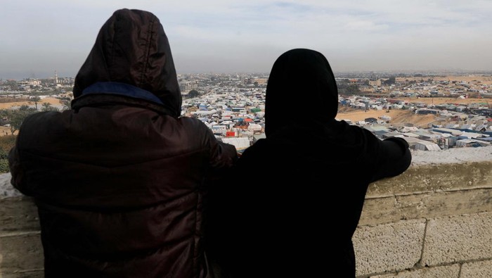 People stand near a tent camp where displaced Palestinians, who fled their houses due to Israeli strikes, take shelter, in Rafah in the southern Gaza Strip January 21, 2024. REUTERS/Saleh Salem