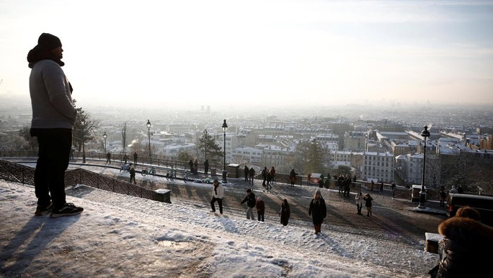 People look at the city skyline near the Sacre Coeur Basilica from the snow-covered Butte Montmartre in Paris as winter weather with snow and cold temperatures hits a northern part of the country, France, January 18, 2024. REUTERS/Benoit Tessier