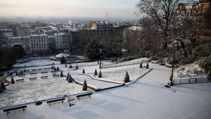 People look at the city skyline near the Sacre Coeur Basilica from the snow-covered Butte Montmartre in Paris as winter weather with snow and cold temperatures hits a northern part of the country, France, January 18, 2024. REUTERS/Benoit Tessier