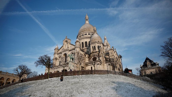 People look at the city skyline near the Sacre Coeur Basilica from the snow-covered Butte Montmartre in Paris as winter weather with snow and cold temperatures hits a northern part of the country, France, January 18, 2024. REUTERS/Benoit Tessier