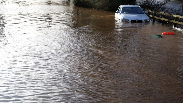 Mobil-mobil Ini Jadi Korban Pohon Tumbang Gegara Badai Isha A car is partially submerged on a flooded road following Storm Isha in Warwick Bridge, Britain, January 22, 2024. REUTERS/Phil Noble