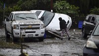 Seorang warga melihat kondisi mobil yang miring akibat tersapu banjir.  