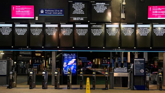A person takes pictures of information boards displaying delayed and cancelled train services on a phone as others wait at the Waverley Station in the aftermath of Storm Isha in Edinburgh, Britain January 22, 2024. REUTERS/Lesley Martin