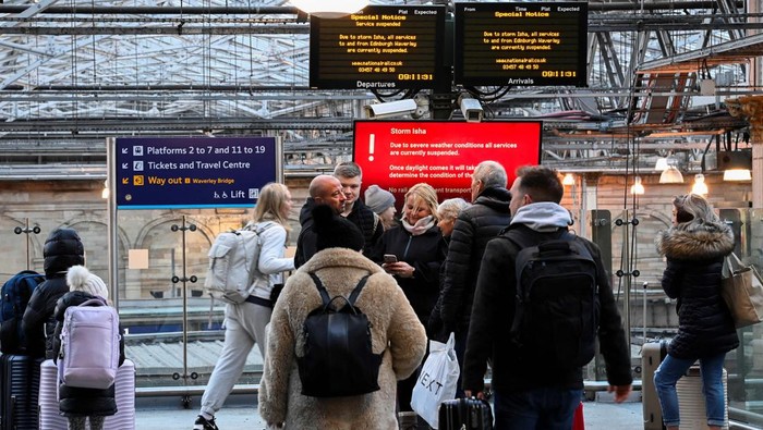 A person takes pictures of information boards displaying delayed and cancelled train services on a phone as others wait at the Waverley Station in the aftermath of Storm Isha in Edinburgh, Britain January 22, 2024. REUTERS/Lesley Martin