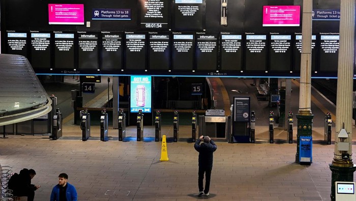 A person takes pictures of information boards displaying delayed and cancelled train services on a phone as others wait at the Waverley Station in the aftermath of Storm Isha in Edinburgh, Britain January 22, 2024. REUTERS/Lesley Martin