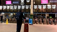 Orang-orang berdiri di depan papan pengumuman di Stasiun Waverley saat kereta dibatalkan akibat Badai Isha di Edinburgh, Inggris 22 Januari 2024.
