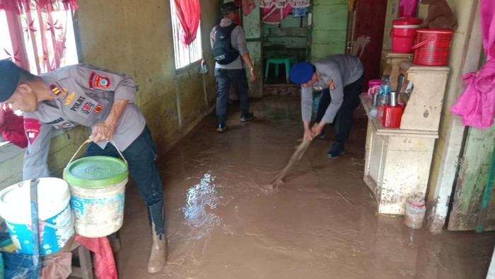 Personel Polres Touna turun membersihkan sisa banjir di rumah warga.