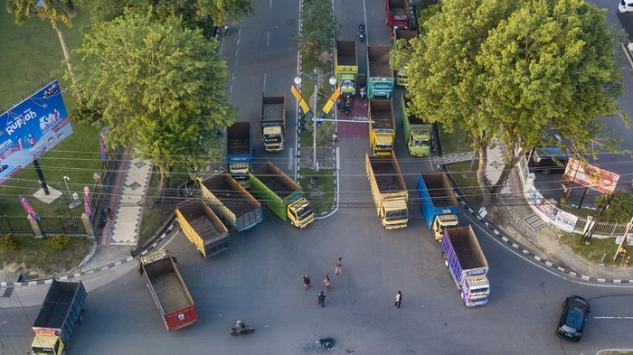 Sopir Truk Batu Bara Tuntut Diizinkan Lagi Lewat Jalan Nasional Foto udara seorang pengemudi berjalan di depan deretan truk pengangkut batu bara yang diparkir saat aksi lanjutan di halaman Kantor Gubernur Jambi, Telanaipura, Jambi, Selasa (23/1/2024). Puluhan sopir pengangkut batu bara itu masih bertahan di lapangan kantor gubernur guna menuntut dibukanya kembali jalan nasional untuk dapat dilalui angkutan batu bara. ANTARA FOTO/Wahdi Septiawan/Spt.
