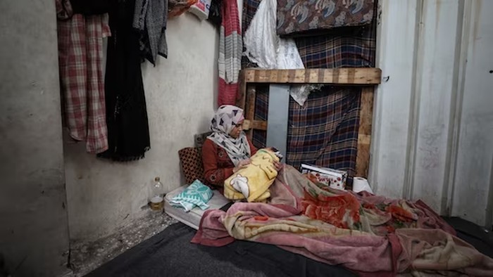 Walaa, seorang wanita Palestina yang terlantar menggendong bayinya yang baru lahir di gudang UNRWA pada hari Senin (22/1/2024) di Rafah, Gaza selatan