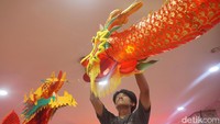 Salah satu penjaga toko di Pasar Atom Mal sedang memasang ornamen naga.