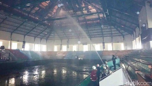 Petugas pemadam kebakaran Badung menyemprotkan air bertenaga tinggi dari dalam bangunan GOR Kerobokan, Rabu (24/1/2024). (Agus Eka detikBali)